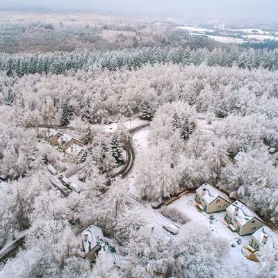 Winter aerial photo of Center Parcs Les Ardennes with a few holiday homes between the trees