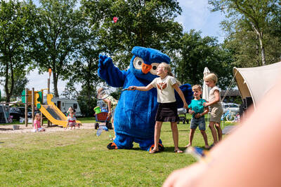 Cobus the owl mascot of Camping Village de Zandstuve with children in the playground