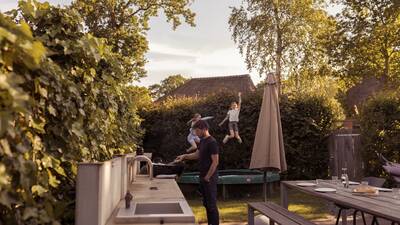 Kinderen springen op een trampoline in de tuin van een villa op vakantiepark Dutchen Park Duynvoet