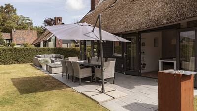Tuin met loungeset, eettafel en barbeque van een luxe vakantiehuis op Dutchen Villapark Mooi Schoorl