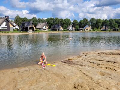 Meisje speelt op het strand bij een vakantiehuis aan het water op Landal Drentse Lagune