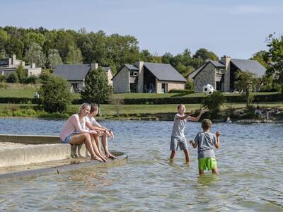 Children play in the water of the recreational lake of the Village l'Eau d'Heure holiday park