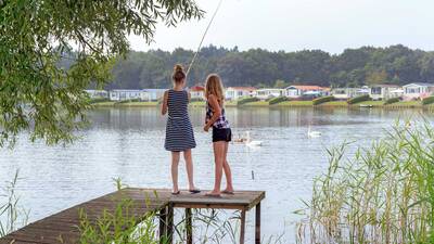 Kinderen aan het vissen in de Agnietenplas vanaf een steiger op Molecaten Park De Agnietenberg