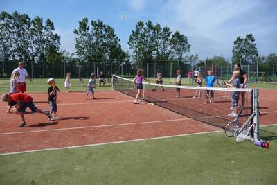 Mensen zijn aan het tennissen op de tennisbaan van Roompot Vakantiepark Callassande