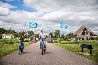 Mensen fietsen bij de ingang van vakantiepark Topparken Park Westerkogge