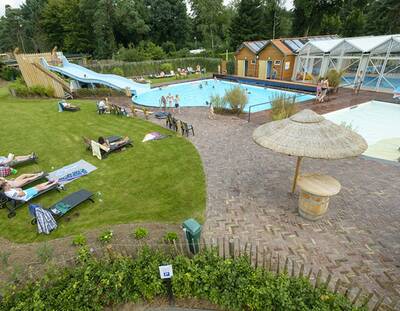 Het buitenbad met brede glijbaan en ligweide van vakantiepark Topparken Resort Veluwe