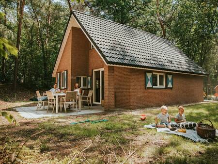 Gezin in de tuin van een vrijstaand vakantiehuis op vakantiepark Beerze Bulten