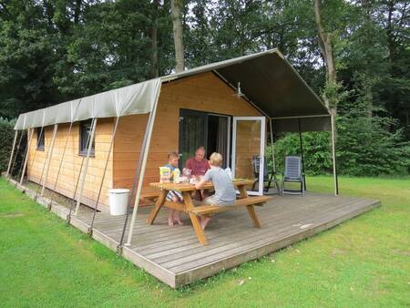 Mensen op de veranda van een Safarilodge op vakantiepark Camping de Noetselerberg