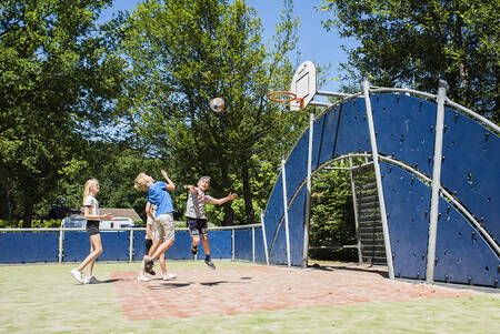 Kinderen aan het basketballen op het speelveld van Camping Vreehorst