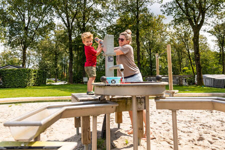 Moeder en kind bij een waterspeeltoestel op vakantiepark De Witte Berg