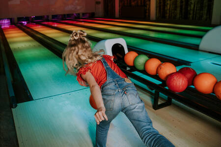 Meisje aan het bowlen op de bowlingbaan van vakantiepark Dierenbos