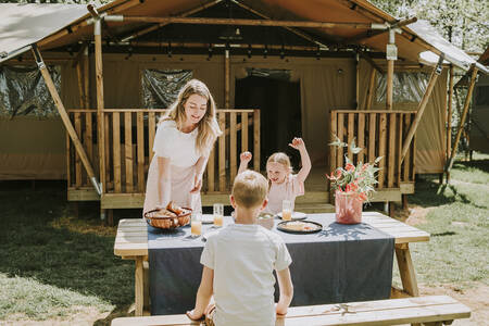 Gezin aan een picknicktafel van een Lodgetent op vakantiepark Dierenbos