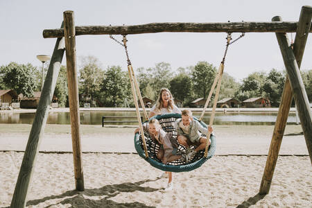 Kinderen op een grote schommel in een speeltuin op vakantiepark Dierenbos