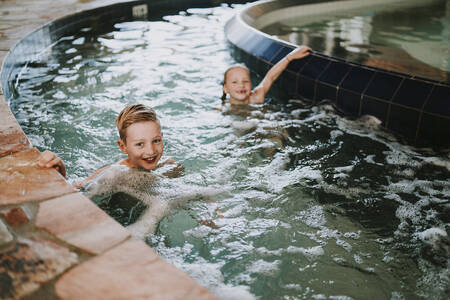 Kinderen zwemmen in de stroomversnelling van het binnenbad van vakantiepark Dierenbos