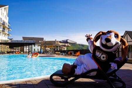 Mascotte Mio op een ligstoel bij het buitenbad van vakantiepark Dormio Eifeler Tor