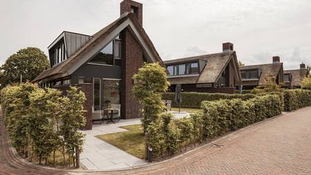 Luxe vakantiehuizen met rieten dak aan een laan op vakantiepark Dutchen Villapark Mooi Schoorl