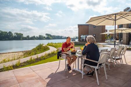 Stel in de tuin van een vrijstaand vakantiehuis aan het water op vakantiepark EuroParcs Aan de Maas