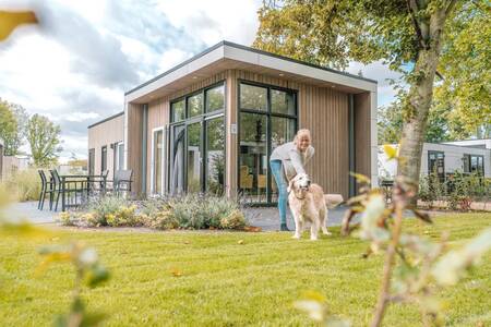 Vrouw met hond in de tuin van een vakantiehuis op vakantiepark Europarcs Bad Hoophuizen