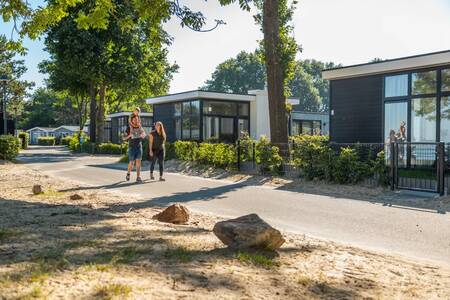Gezin wandelt voor enkele vakantiehuizen op vakantiepark Europarcs Bad Hoophuizen
