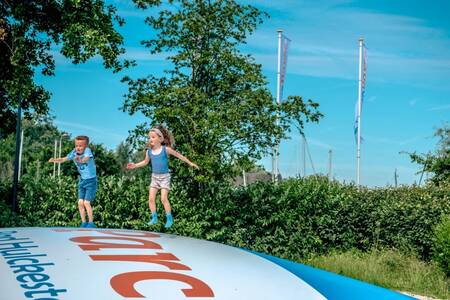 Kinderen springen op de airtrampoline in een speeltuin op vakantiepark EuroParcs Bad Hulckesteijn
