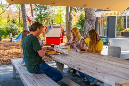 Gezin eet patat op het terras van het restaurant op vakantiepark EuroParcs Beekbergen
