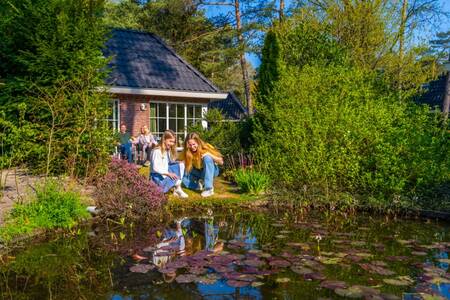 Gezin in de tuin van een vakantiehuis aan het water op vakantiepark EuroParcs Beekbergen