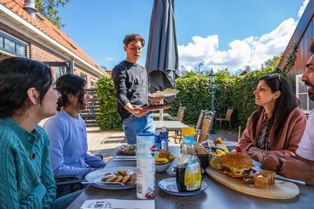 Gezin aan het eten op het terras van het restaurant op vakantiepark EuroParcs Buitenhuizen