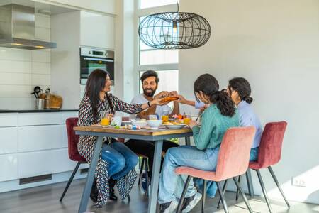 Gezin aan het eten in de keuken van een vakantiehuis op vakantiepark EuroParcs Buitenhuizen