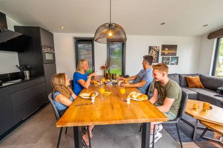 Mensen aan de keukentafel in een vakantiehuis op vakantiepark EuroParcs De Hooge Veluwe