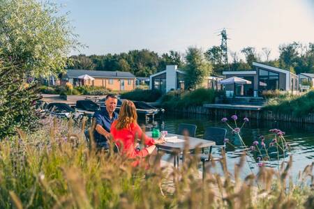 Een stel op een steiger bij een vakantiehuis op vakantiepark EuroParcs De Kraaijenbergse Plassen