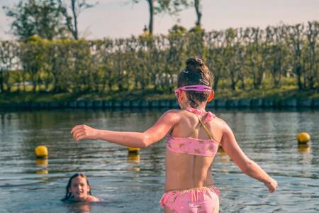 Kinderen zwemmen in het water bij het strand van vakantiepark EuroParcs De Rijp