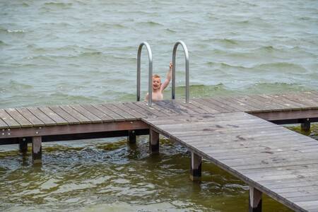 Kind hangt aan de steiger op vakantiepark EuroParcs De Wiedense Meren