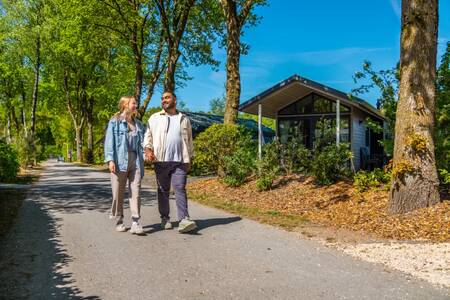 Stelletje wandelt voor een vakantiehuis op vakantiepark EuroParcs De Wije Werelt