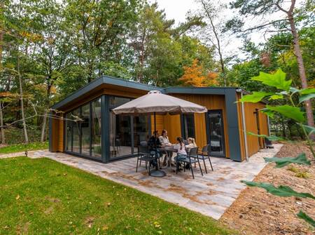 Gezin aan tafel in de tuin van een chalet op vakantiepark EuroParcs de Wiltzangh