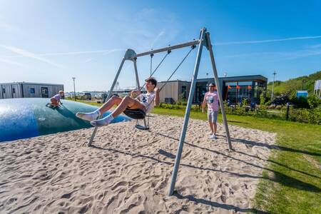 Kind op de schommel in de speeltuin op vakantiepark EuroParcs Enkhuizer Strand