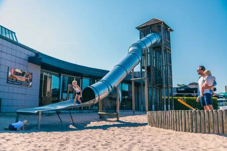 Kind glijdt van de glijbaan in een speeltuin op vakantiepark Europarcs EuroParcs Zilverstrand