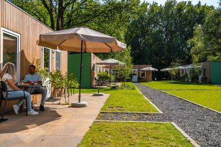 Stel zit in de tuin van een chalet op vakantiepark Europarcs Het Amsterdamse Bos