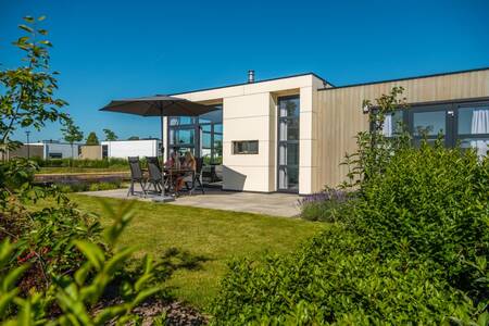 Mensen zitten op tuinmeubels in de tuin van een chalet op vakantiepark EuroParcs Marina Strandbad