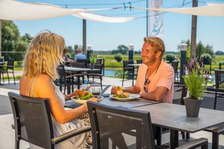 Stel op het terras van het restaurant op vakantiepark EuroParcs Marina Strandbad