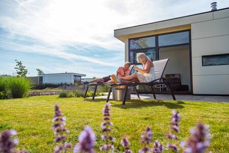 Een paar ontspant in de tuin van een vakantiehuis op vakantiepark EuroParcs Marina Strandbad