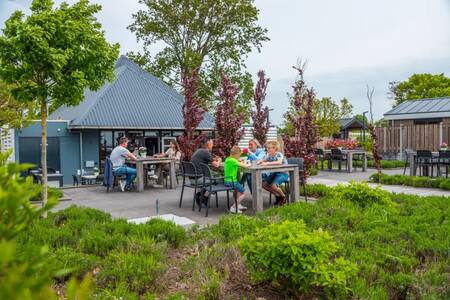 Mensen aan het eten op het terras van de snackbar op vakantiepark EuroParcs Markermeer