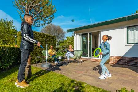 Gezin aan het ontspannen in de tuin van een vakantiehuis op vakantiepark EuroParcs Molengroet