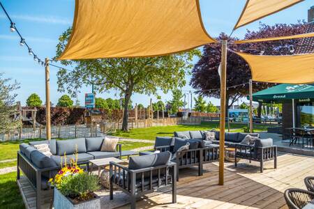 Loungestoelen op het terras van het restaurant op vakantiepark EuroParcs Poort van Maastricht