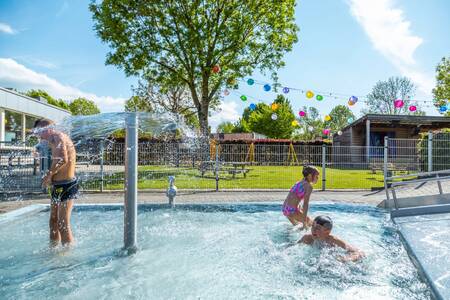 Kinderen spetteren in het buitenbad van vakantiepark EuroParcs Poort van Maastricht