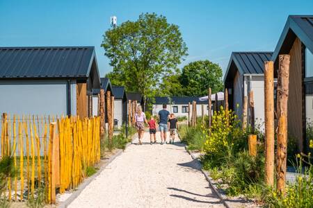 Gezin wandelt over een pad tussen vakantiehuizen op vakantiepark EuroParcs Poort van Zeeland