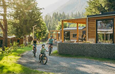 Gezin fietst over een laan langs vakantiehuizen op vakantiepark EuroParcs Pressegger See