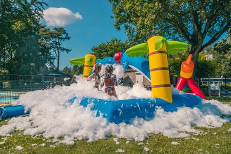 Kinderen spelen in het schuim op een luchtkussen op vakantiepark EuroParcs Reestervallei