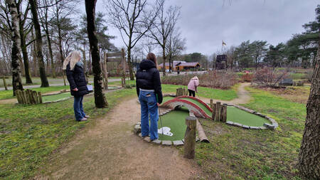 Gezin speelt golf op de minigolfbaan van vakantiepark EuroParcs Ruinen
