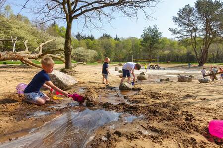 Kinderen spelen met zand en water in de natuurspeeltuin op vakantiepark EuroParcs Ruinen