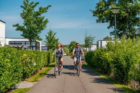 Stel fietst tussen vakantiehuizen op vakantiepark EuroParcs Schoneveld